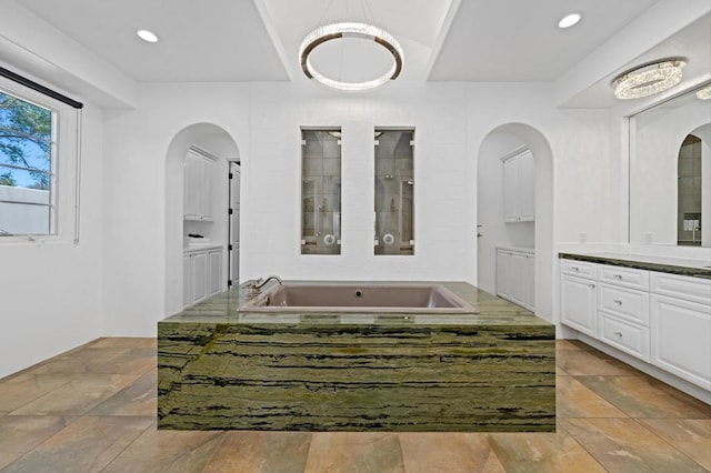 bathroom featuring vanity and a relaxing tiled tub