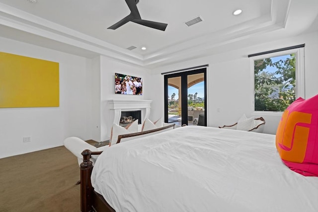 bedroom featuring ceiling fan, carpet, a tray ceiling, and access to outside