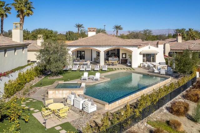 rear view of property featuring a swimming pool with hot tub and a patio