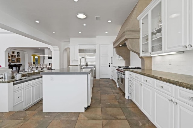 kitchen with premium appliances, white cabinets, decorative backsplash, sink, and a kitchen island with sink