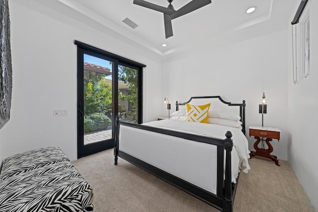 bedroom featuring light colored carpet, access to exterior, a tray ceiling, and ceiling fan