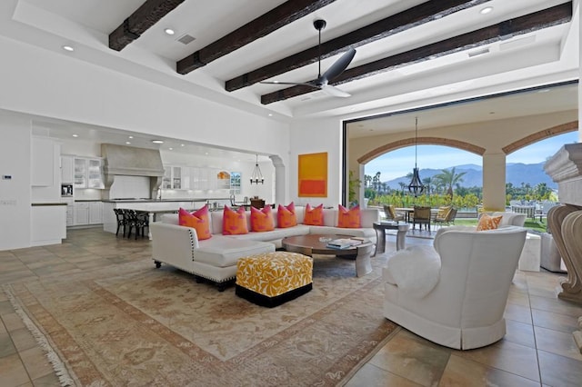 living room with a mountain view, beam ceiling, and ceiling fan with notable chandelier