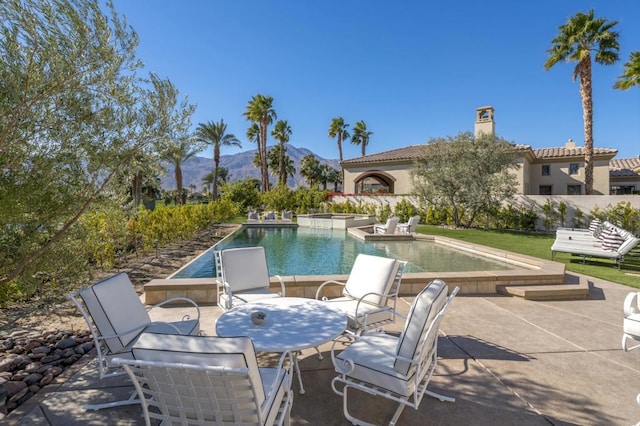 view of pool featuring a mountain view, a patio area, and a jacuzzi