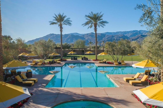 view of pool featuring a mountain view, an in ground hot tub, and a lawn