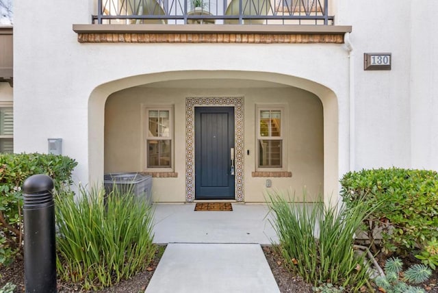 view of exterior entry featuring a balcony and central air condition unit