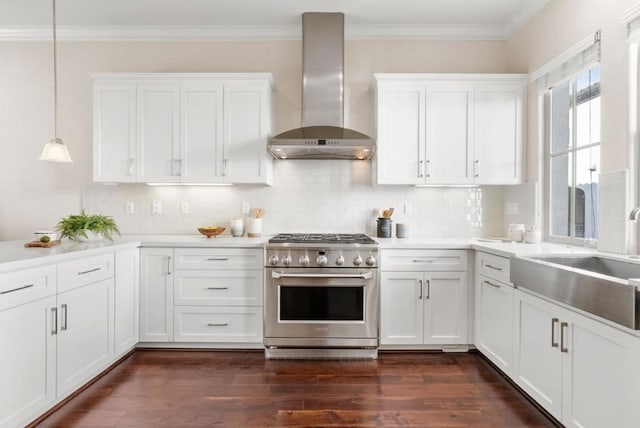 kitchen featuring hanging light fixtures, high end stainless steel range oven, white cabinets, and wall chimney exhaust hood