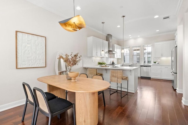 kitchen with white cabinetry, wall chimney range hood, pendant lighting, and appliances with stainless steel finishes