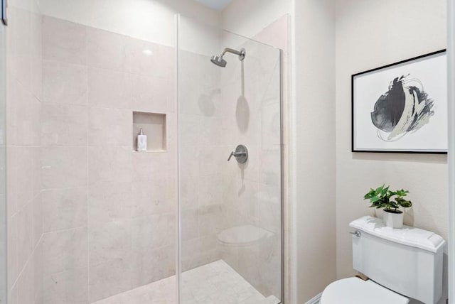 bathroom featuring a tile shower and toilet