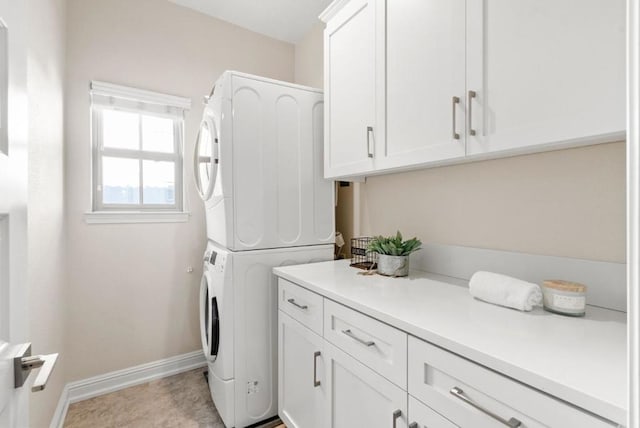 clothes washing area featuring cabinets and stacked washer / drying machine