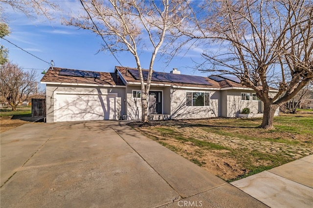 single story home with a garage and solar panels