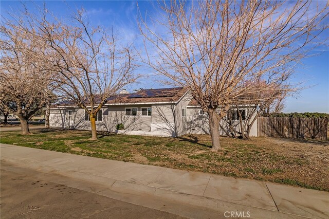 view of front of home with solar panels and a front yard