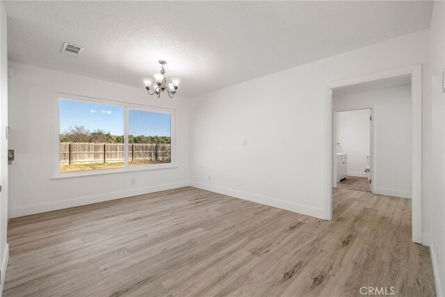 266 E Fig Ln, Corning, CA 96021 - empty room featuring light hardwood / wood-style floors, a chandelier, and a textured ceiling