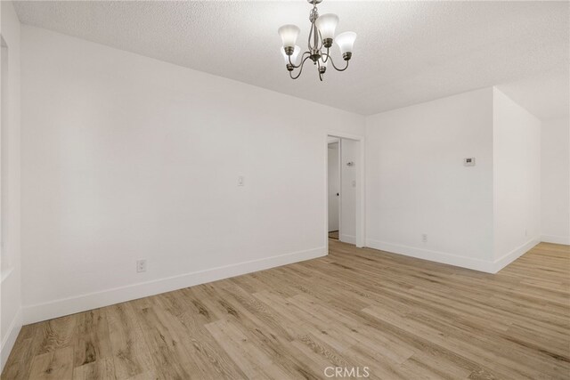 266 E Fig Ln, Corning, CA 96021 - unfurnished room with light hardwood / wood-style flooring, a chandelier, and a textured ceiling