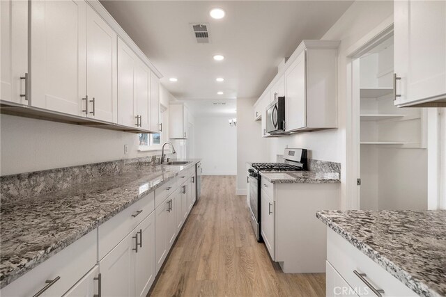 266 E Fig Ln, Corning, CA 96021 - kitchen with sink, stainless steel appliances, light stone countertops, and white cabinets
