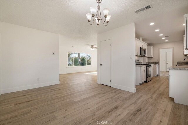 266 E Fig Ln, Corning, CA 96021 - kitchen featuring light hardwood / wood-style flooring, stainless steel appliances, white cabinets, pendant lighting, and ceiling fan with notable chandelier