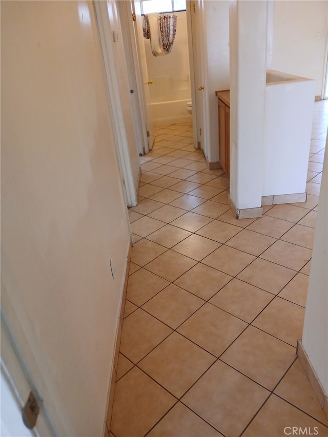 hall featuring light tile patterned flooring and baseboards