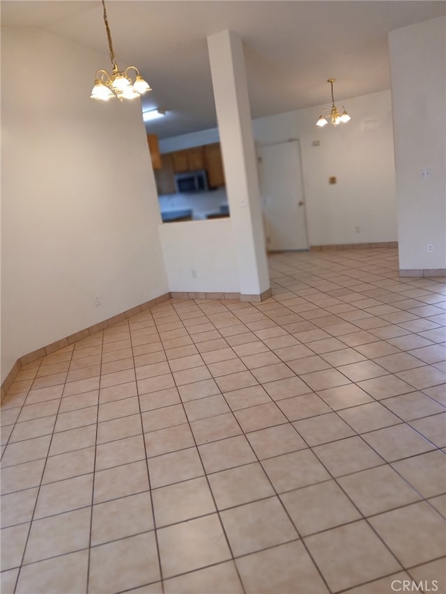 empty room with a notable chandelier, baseboards, and light tile patterned floors