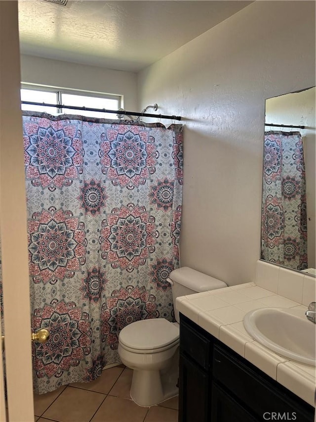 bathroom with a shower with curtain, vanity, toilet, and tile patterned floors