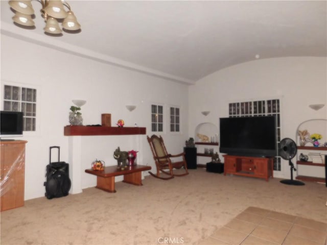 carpeted living room featuring lofted ceiling and an inviting chandelier