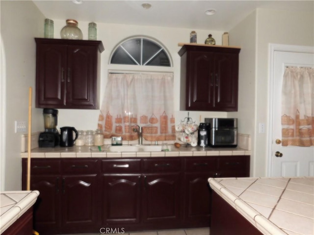 kitchen featuring tile countertops, sink, and dark brown cabinets