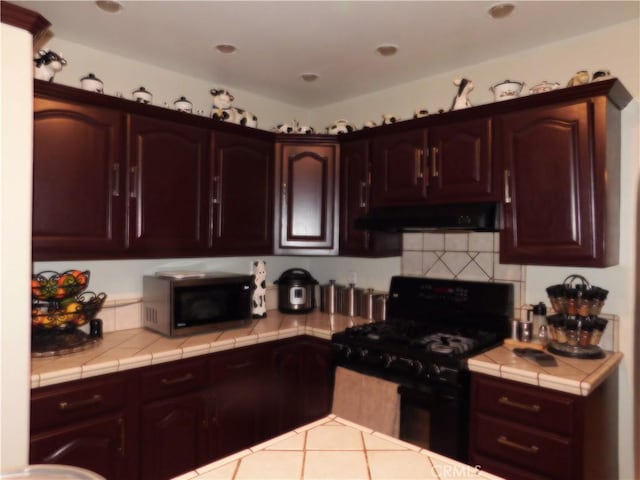 kitchen with dark brown cabinetry, black range, ventilation hood, and tile countertops