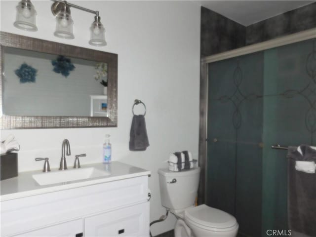 bathroom featuring vanity, toilet, and a shower with shower door