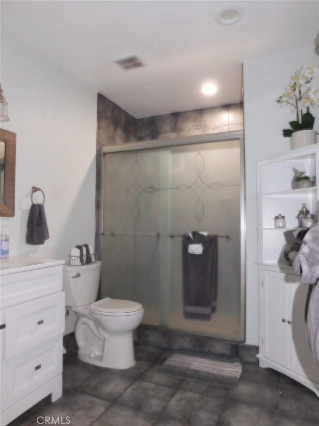 bathroom featuring vanity, toilet, and a shower with door