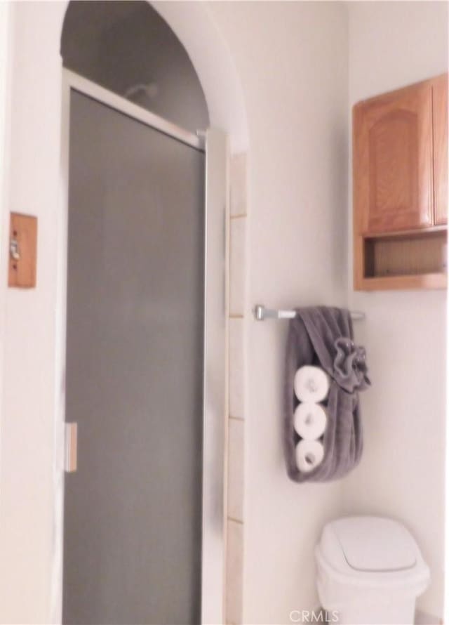 bathroom featuring walk in shower and toilet