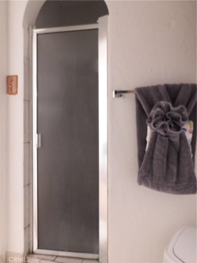 bathroom with toilet and a shower with shower door