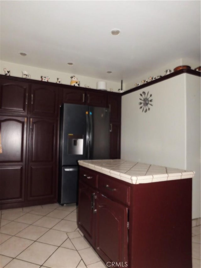 kitchen featuring light tile patterned flooring, tile countertops, and refrigerator with ice dispenser