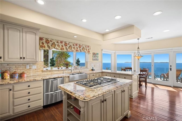 kitchen featuring a kitchen island, a water view, hanging light fixtures, and decorative backsplash