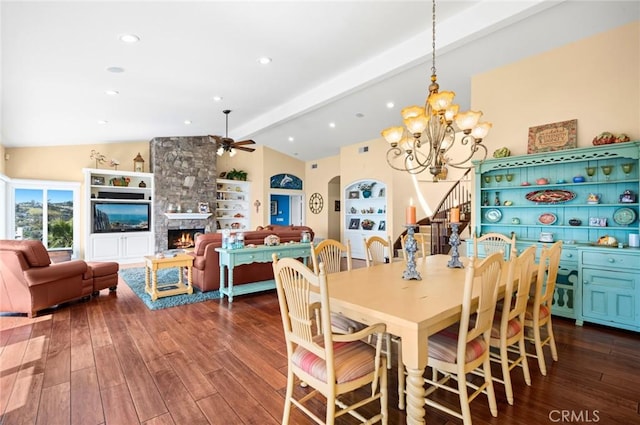 dining area featuring hardwood / wood-style flooring, ceiling fan with notable chandelier, lofted ceiling with beams, and a fireplace