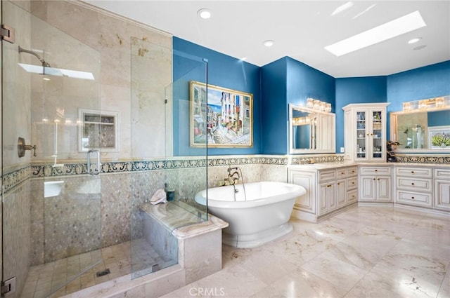 bathroom with tile walls, vanity, a skylight, and shower with separate bathtub