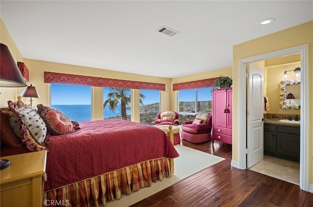 bedroom featuring sink, connected bathroom, and a water view