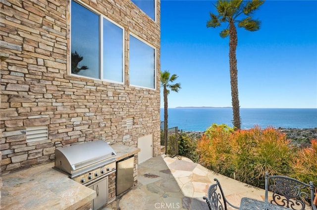 view of patio / terrace featuring an outdoor kitchen, a water view, and grilling area