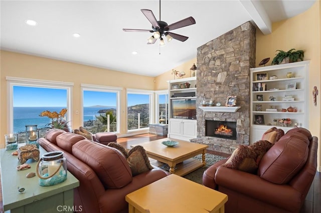 living room with ceiling fan, a water view, a fireplace, and lofted ceiling with beams