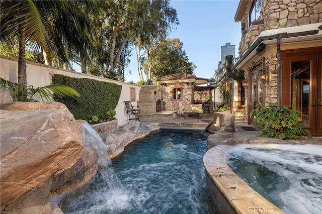 view of pool featuring pool water feature and an outdoor stone fireplace