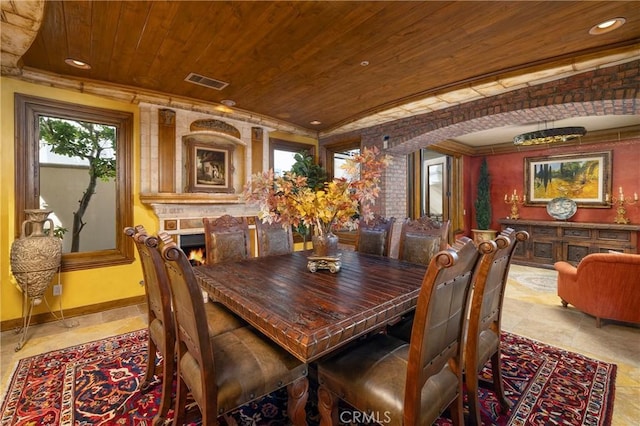 dining room featuring a large fireplace and wooden ceiling