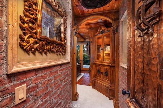 hallway with wooden ceiling and brick wall