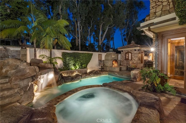 pool at twilight featuring a patio area and an in ground hot tub