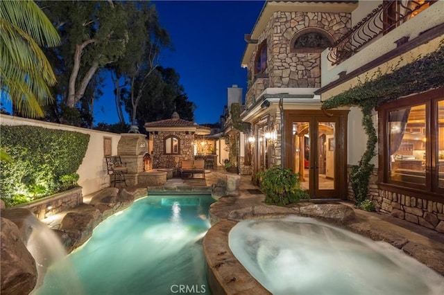 pool at twilight with an in ground hot tub, a patio, and french doors