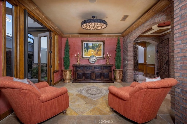 living area featuring crown molding and brick wall