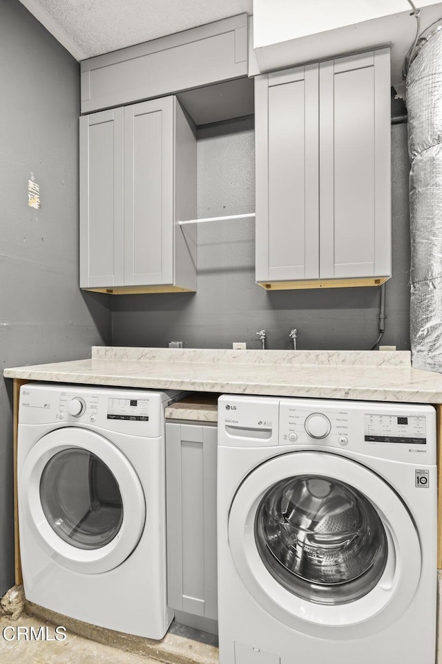 laundry room with cabinets, separate washer and dryer, and a textured ceiling