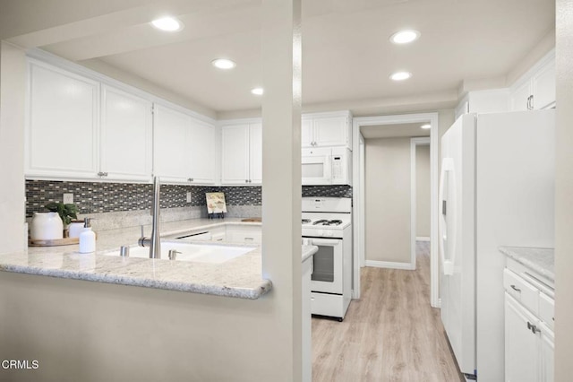 kitchen featuring white cabinetry, light stone counters, white appliances, and kitchen peninsula