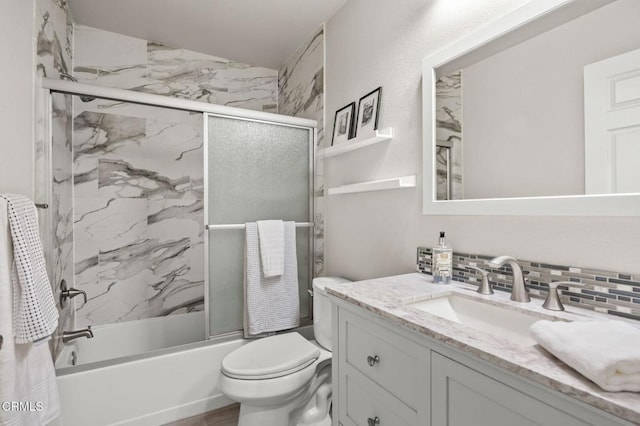 full bathroom with vanity, backsplash, shower / bath combination with glass door, and toilet