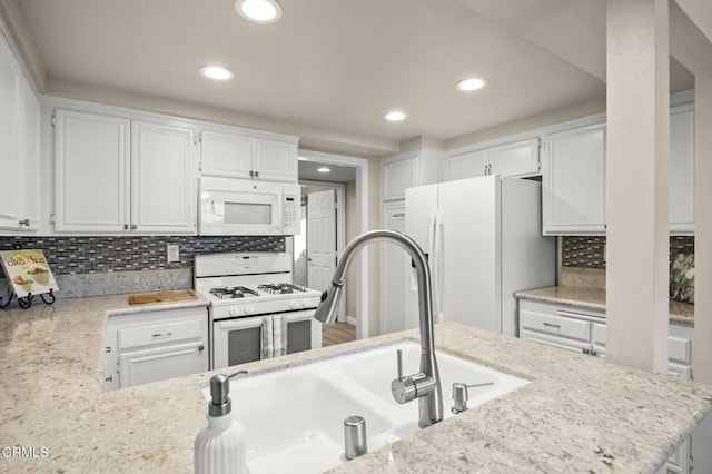 kitchen with tasteful backsplash, white appliances, sink, and white cabinets