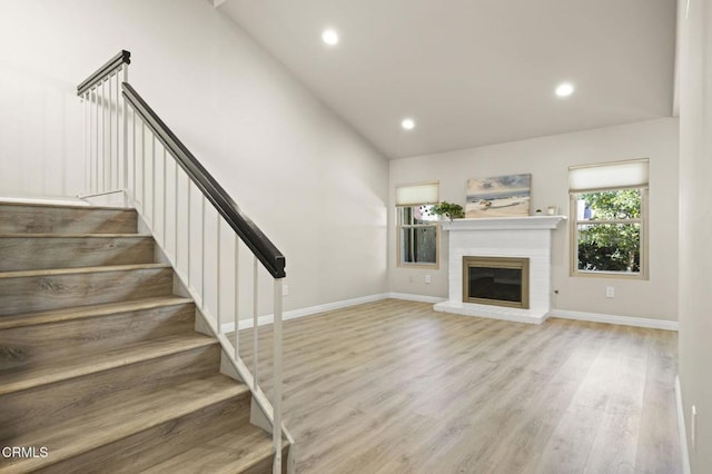 unfurnished living room with lofted ceiling, a fireplace, and light hardwood / wood-style floors