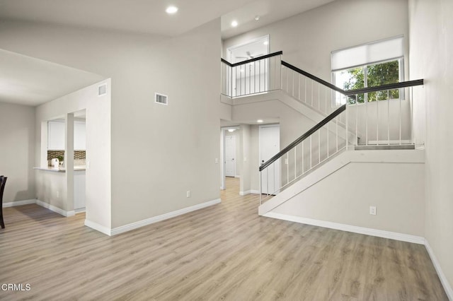 unfurnished living room featuring a high ceiling and light wood-type flooring