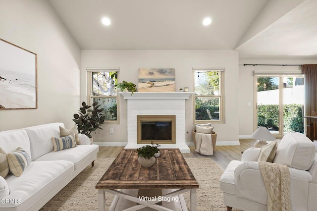 living room with lofted ceiling, a healthy amount of sunlight, and light hardwood / wood-style floors