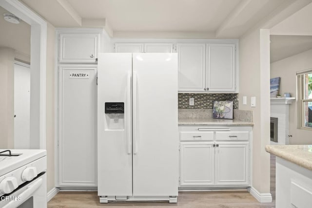 kitchen with white appliances, light hardwood / wood-style floors, and white cabinets